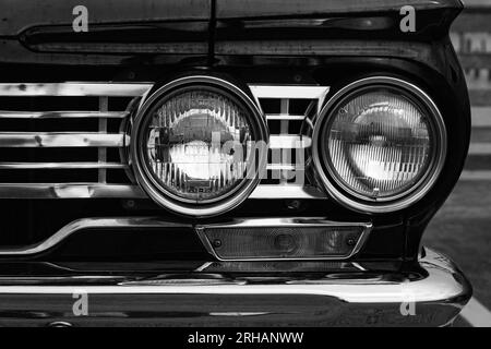 Klassische Autoscheinwerfer Nahaufnahme. Scheinwerfer eines schwarzen Oldtimers. Klassisches Fahrzeugkonzept in Schwarz. Details des Luxuswagens vorn, Foto in Schwarz und Stockfoto