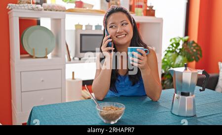 Junge chinesin beim Frühstück, die sich im Speisesaal mit dem Smartphone unterhielt Stockfoto