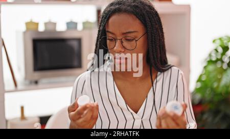 Eine afroamerikanische Frau, die im Esszimmer Pillen in der Hand hat Stockfoto