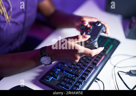 Eine afroamerikanische Frau, die Videospiele mit dem Joystick im Spielzimmer spielt Stockfoto