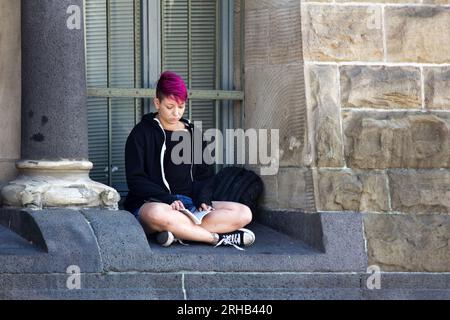 Metz, Frankreich - 20. September 2017: Mädchen liest Buch, sitzt in der Fensternische auf der Straße, sitzt in Lotus-Pose, liest Mädchen. Straßenskizzen Stockfoto