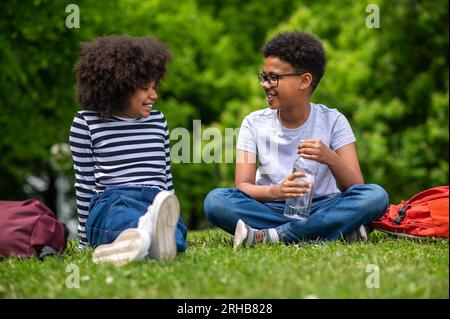 Zwei afroamerikanische Kinder sitzen auf dem Gras im Park Stockfoto