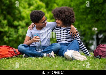 Zwei afroamerikanische Kinder sitzen auf dem Gras im Park Stockfoto