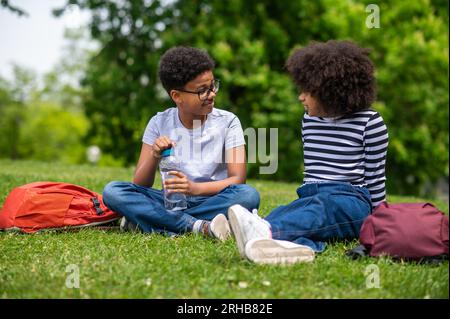 Zwei afroamerikanische Kinder sitzen auf dem Gras im Park Stockfoto