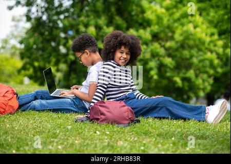 Zwei lockige Teenager sitzen auf dem Gras im Park und fühlen sich gut Stockfoto