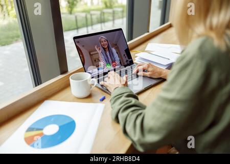 Unternehmerin, die mit dem Kunden per Videokonferenz spricht, während sie im Café sitzt. Konzept der Abstandsarbeit Stockfoto