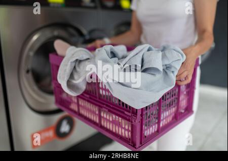 Eine Frau, die eine qualifizierte Waschmaschine im öffentlichen Raum benutzt, um ihre Tücher zu waschen. Stockfoto