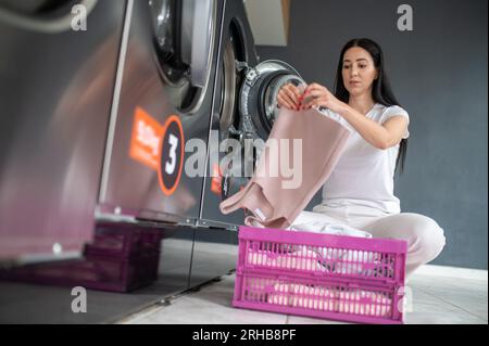 Eine Frau, die eine qualifizierte Waschmaschine im öffentlichen Raum benutzt, um ihre Tücher zu waschen. Stockfoto