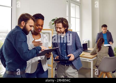 Multinationales Unternehmensteam, das im Büro steht und sich einige Dokumente anschaut Stockfoto