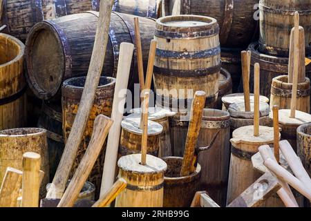Authentische alte Holzfässer in verschiedenen Größen mit Metallreifen, Butterurnen, Holzutensilien Stockfoto
