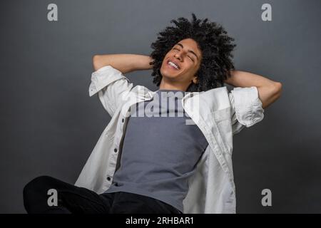 Ein junger, lockiger Kerl, der entspannt sitzt Stockfoto