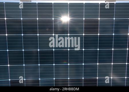 Nahaufnahme eines Sonnenkollektors, der die Sonne reflektiert. Es wandelt Sonnenlicht in Elektrizität um, indem es Photovoltaikzellen verwendet. Stockfoto