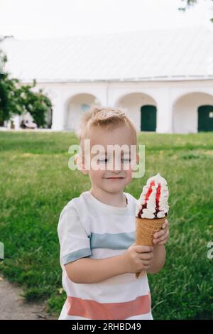 Porträt eines kleinen Jungen. Ein Baby isst einen köstlichen Eisbecher. Glückliches Kind. Sommertag Stockfoto