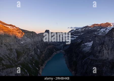 Epischer Sonnenuntergang über einem alpinen See namens Limmerensee in der Schweiz. Wundervolle Landschaft in den alpen. Die Sonne scheint zu den Gipfeln der Berge. Stockfoto