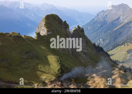 Fantastischer Wandertag in den alpen der Schweiz. Eine schöne Lokomotive fährt auf einen Berg und es kommt viel Rauch aus der Lokomotive. Stockfoto