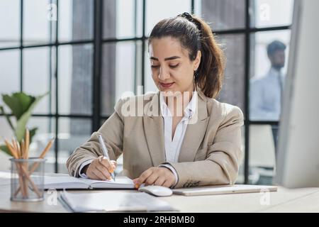 Professionelle Frau am Schreibtisch, die am Computer mit E-Mails arbeitet und Artikel in einer digitalen Marketingagentur schreibt. Stockfoto