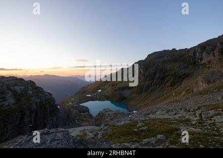 Ein wunderbarer Blick auf den Horizont bei einem wunderschönen Sonnenuntergang in den alpen der Schweiz an einem alpinen See namens Schottensee. Stockfoto