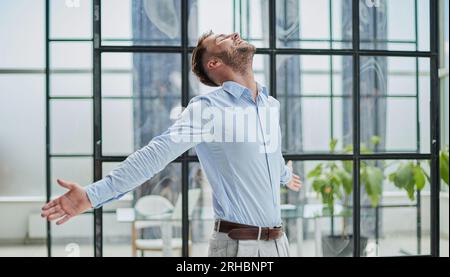 Porträt mit Kopfschuss und lächelndem selbstbewusstem Geschäftsmann im modernen Büro Stockfoto