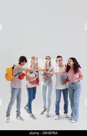 Gruppe von Schülern, die ihre Hände auf hellem Hintergrund zusammenlegen Stockfoto