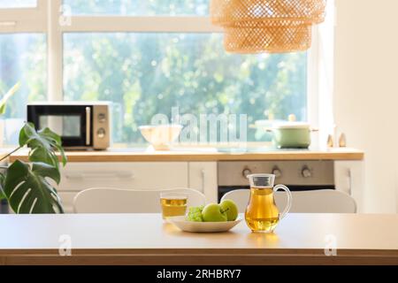 Kanne mit einem Glas Saft und Obst auf dem Esstisch in der Küche Stockfoto