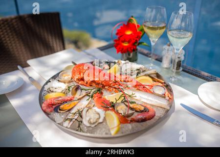 Spektakulärer Hummer mit Muscheln, Garnelen, Muscheln und Rasiermuscheln auf einem Eisteller mit spektakulärem Meerblick auf Mallorca. Stockfoto