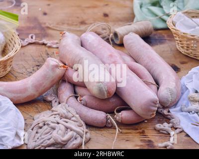 Von oben ein Haufen frischer roher Chorizo-Würste mit Hülsen und Fäden, die in der traditionellen spanischen Metzgerei auf einen Holztisch gelegt werden Stockfoto