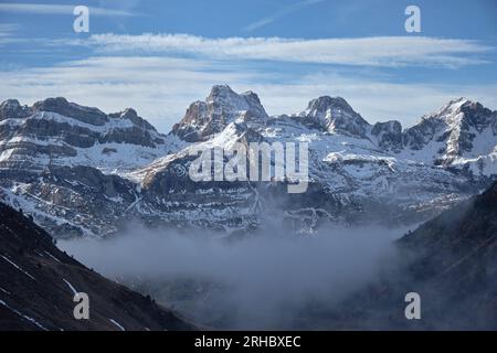 Dichter Nebel bedeckt das Tal mit schneebedeckten Bergen und wolkenblauem Himmel an sonnigen Wintertagen in der Natur Stockfoto