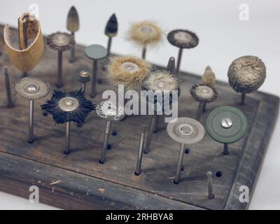 Von oben ein Satz verschiedener Metall-Dentalschleifer mit Schleifpapier zum Polieren von Zähnen auf einer Holzwanne vor weißem Hintergrund Stockfoto