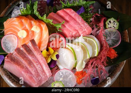 Von oben genießen Sie köstliche Sashimi mit frischem Gemüse und Meeresfrüchten, serviert auf einem Holztisch im asiatischen Restaurant Stockfoto