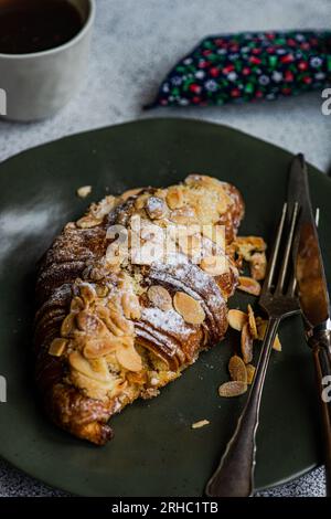 Nahaufnahme eines Mandelcroissants mit einer Tasse schwarzem Kaffee Stockfoto