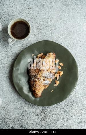 Blick von oben auf ein Mandelcroissant mit einer Tasse schwarzem Kaffee Stockfoto