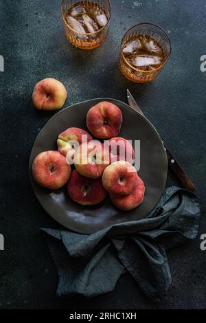 Zwei Gläser Eistee neben einer Schüssel flacher Pfirsiche Stockfoto