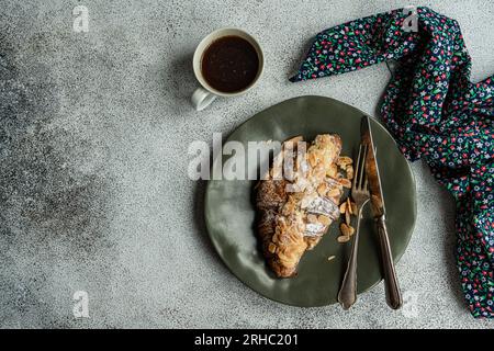Blick von oben auf ein Mandelcroissant mit einer Tasse schwarzem Kaffee Stockfoto