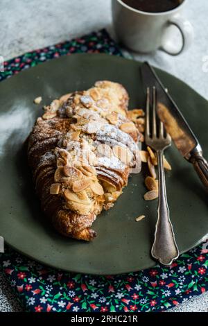 Nahaufnahme eines Mandelcroissants mit einer Tasse schwarzem Kaffee Stockfoto