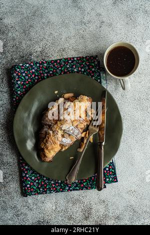 Blick von oben auf ein Mandelcroissant mit einer Tasse schwarzem Kaffee Stockfoto