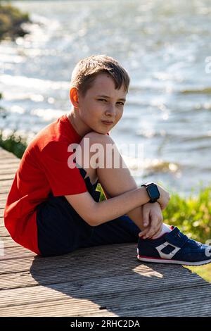 Porträt eines Jungen, der im Sommer am See sitzt Stockfoto