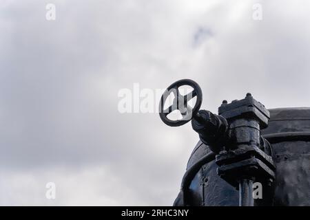 Schwarz lackiertes Dampflokomotiveisen, das das Rad schließt, grauer bewölkter Himmel im Hintergrund Stockfoto