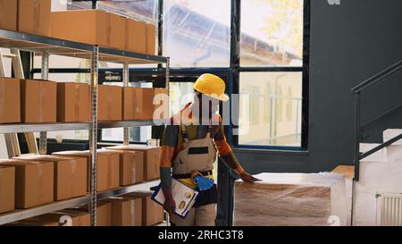 Verschiedene Kollegen überprüfen die Warteliste auf Papieren und überprüfen das Liefersystem, bevor sie an der Sendung arbeiten. Mann und Frau, die an Warenbeständen im Lager arbeiten, Qualitätskontrolle. Stockfoto