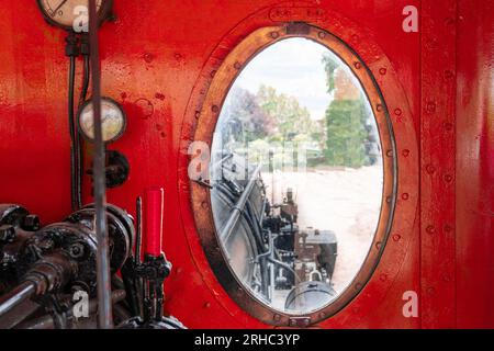 Blick vom Fenster auf das rot lackierte Fahrerhaus einer alten Dampflokomotive Stockfoto