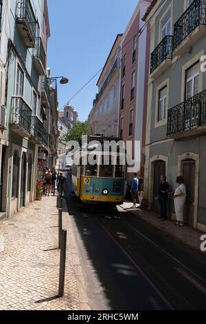 Man sieht Leute in der Nähe einer Straßenbahn in einer der Straßen von Barrio Alto in Lissabon laufen. Stockfoto