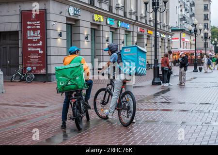 Zwei Yandex Food Kuriere auf Fahrrädern mit großen Thermosäcken in der Stary Arbat Straße in Moskau. Moskau. Russland. August 2023. Stockfoto