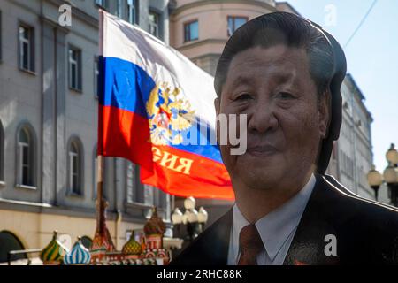 Moskau, Russland. 15. August 2023. Nahaufnahme eines Fotos des chinesischen Führers Xi Jinping in voller Länge vor dem Hintergrund einer russischen Flagge, die in der Nähe eines Souvenirladens in der Arbat Street im Zentrum von Moskau, Russland, installiert wurde Stockfoto