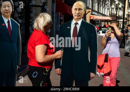 Moskau, Russland. 15. August 2023. Frauen machen ein Foto mit einem Foto des chinesischen Führers Xi Jinping und des Präsidenten der Russischen Föderation Wladimir Putin Against, der in der Nähe eines Souvenirladens in der Arbat Street im Zentrum von Moskau, Russland, installiert ist Stockfoto