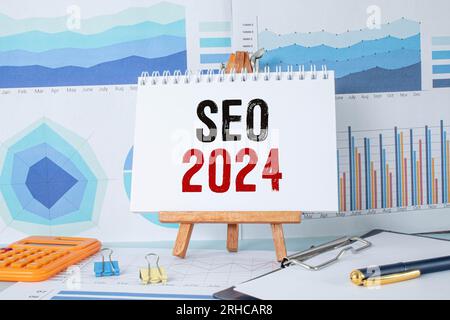 Auf der Lupe befinden sich Papierstreifen mit der Aufschrift SEO 2024 Stockfoto