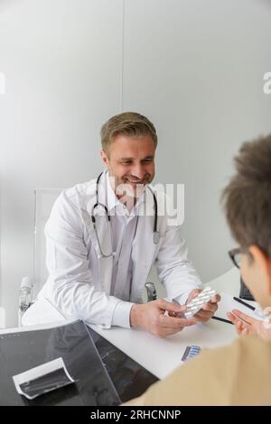 Nahaufnahme eines lächelnden Arztes, der einer Patientin während des Arzttermins Pillen verschreibt Stockfoto