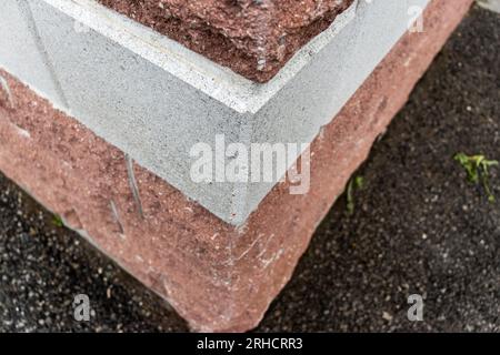 Weiß lackierte Betonecke mit Gras - abgesplitterte und raue Textur - verwischte Ziegelwand und geschliffener Hintergrund Stockfoto