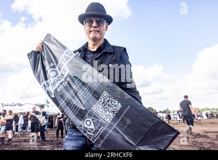 Wacken, Deutschland. 03. Aug. 2023. Christian Maria Mäntele, Leiterin des Projekts #17Goals bei der Engagement Global gGmbH, zeigt auf dem Festivalgelände einen Müllsack mit einem QR-Code. Mäntele versucht, mit dem Trash Metal Project in Zusammenarbeit mit Festivalveranstaltern die Themen Abfallvermeidung und Recycling unter die Metallköpfe zu bringen. (Zu dpa-KORR: 'Festivals wollen nachhaltiger werden - aber wie?') Kredit: Axel Heimken/dpa/Alamy Live News Stockfoto