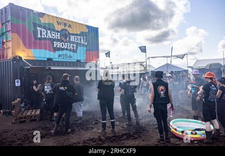 Wacken, Deutschland. 03. Aug. 2023. Besucher des Festivals stehen vor dem Container des Trash Metal Project auf dem Festgelände. In Zusammenarbeit mit den Veranstaltern des Festivals versucht das Trash Metal Project, die Themen Abfallvermeidung und Recycling unter die Metallköpfe zu bringen. (Zu dpa-KORR: 'Festivals wollen nachhaltiger werden - aber wie?') Kredit: Axel Heimken/dpa/Alamy Live News Stockfoto