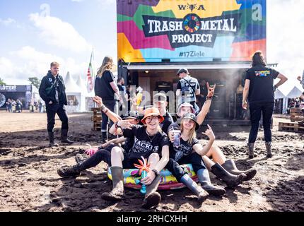 Wacken, Deutschland. 03. Aug. 2023. Festivalbesucher sitzen in einem Swimmingpool vor dem Container des Trash Metal Project auf dem Festivalgelände. In Zusammenarbeit mit den Veranstaltern des Festivals versucht das Trash Metal Project, die Themen Abfallvermeidung und Recycling unter die Metallköpfe zu bringen. (Zu dpa-KORR: 'Festivals wollen nachhaltiger werden - aber wie?') Kredit: Axel Heimken/dpa/Alamy Live News Stockfoto