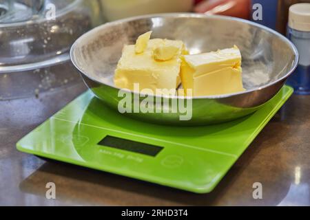 Butter in Metallplatte im digitalen Maßstab in der Hausküche Stockfoto
